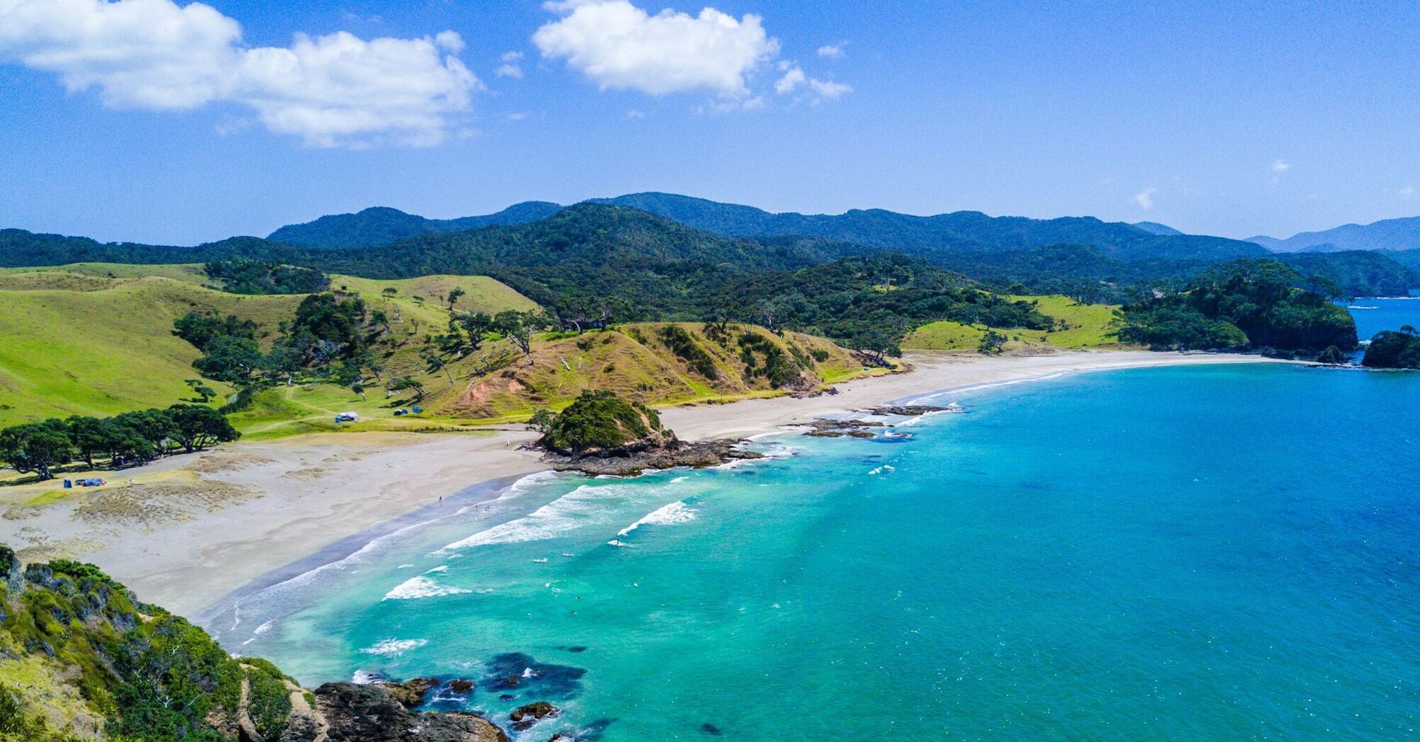 Scenic coastal landscape of a beach in New Zealand with turquoise waters and green hills