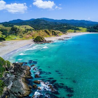 Scenic coastal landscape of a beach in New Zealand with turquoise waters and green hills