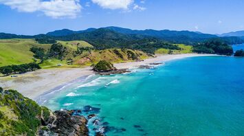 Scenic coastal landscape of a beach in New Zealand with turquoise waters and green hills