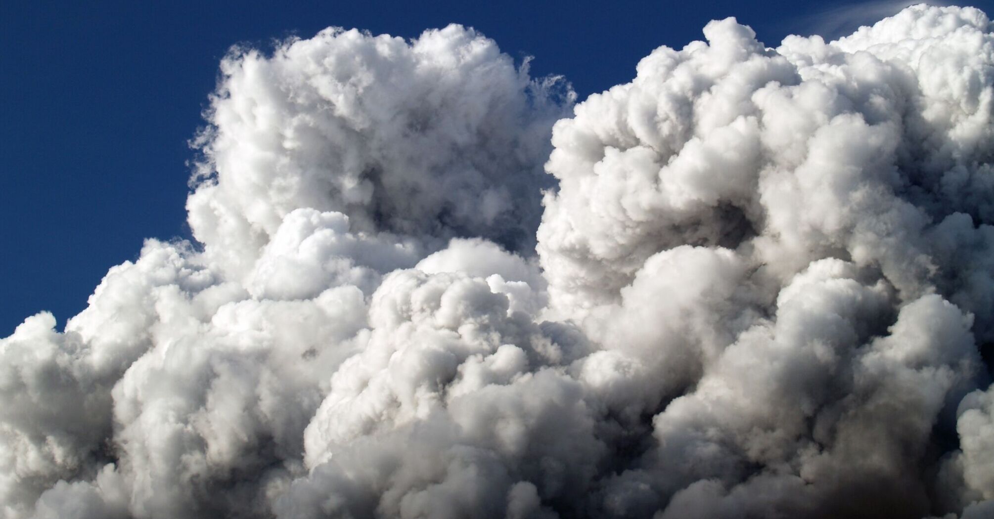 Thick clouds of smoke rise against a blue sky