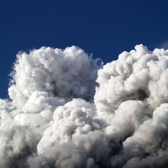 Thick clouds of smoke rise against a blue sky