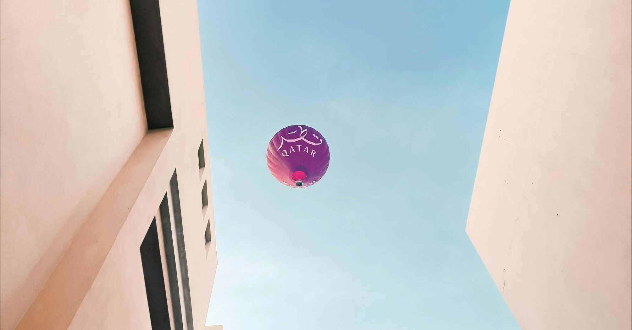 a purple balloon flying in the air between two buildings