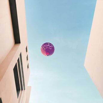 a purple balloon flying in the air between two buildings