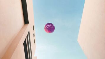 a purple balloon flying in the air between two buildings