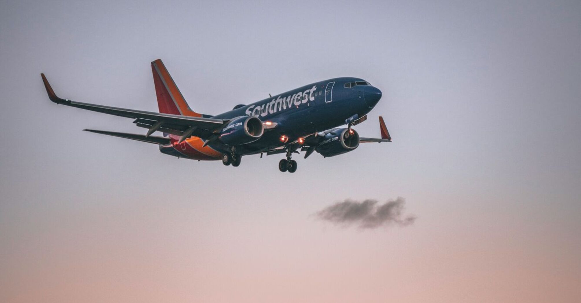 A Southwest Airlines plane flying at sunset with palm trees in the foreground