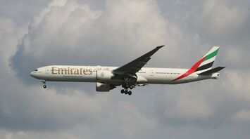 Emirates aircraft flying mid-air against a cloudy sky backdrop