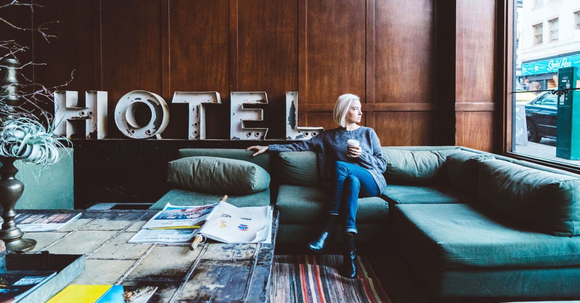 Woman sitting in a hotel lobby with a coffee, looking out the window