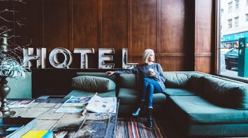 Woman sitting in a hotel lobby with a coffee, looking out the window