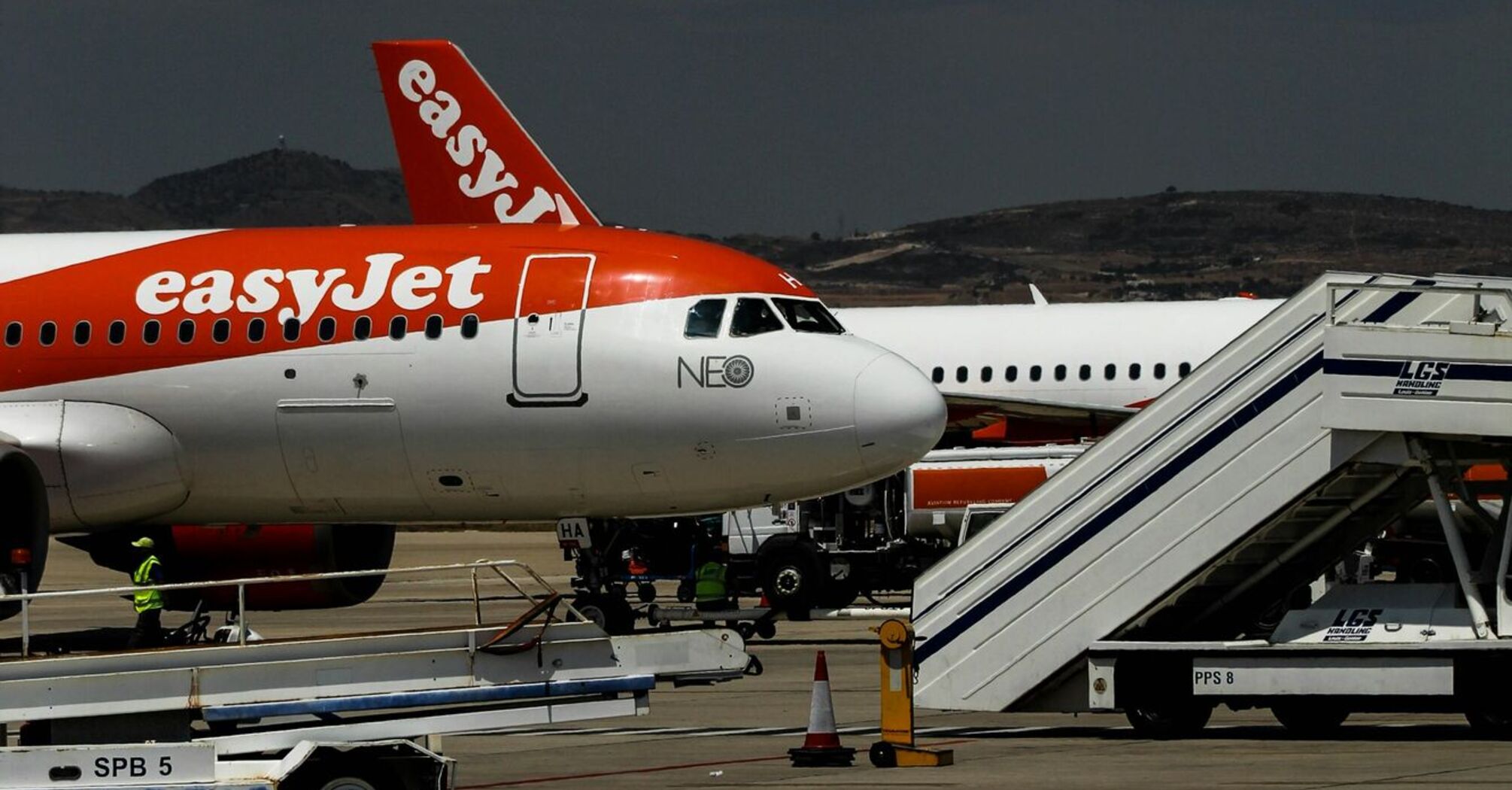 An easyJet airplane parked at the airport with ground staff preparing for boarding