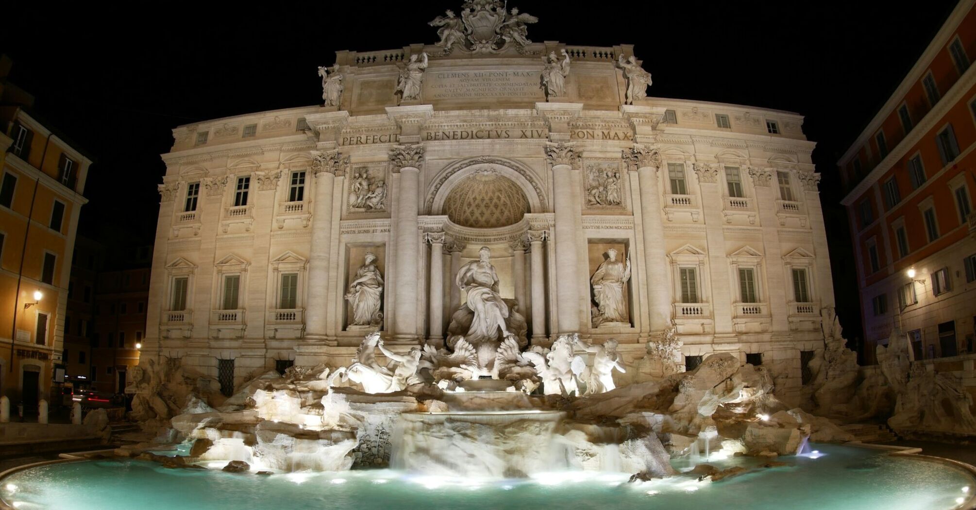 Night view of the illuminated Trevi Fountain in Rome, showcasing its detailed sculptures and architecture