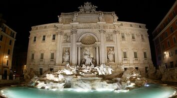 Night view of the illuminated Trevi Fountain in Rome, showcasing its detailed sculptures and architecture