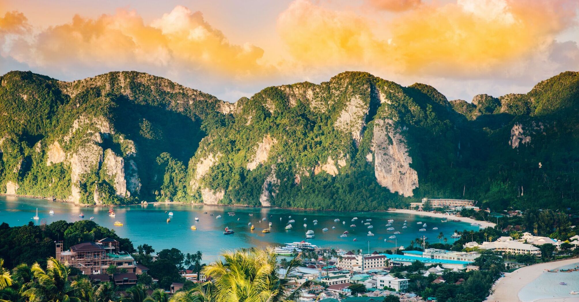 Tropical island bay with boats and sunset