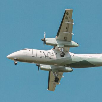 Widerøe regional aircraft flying in clear blue sky