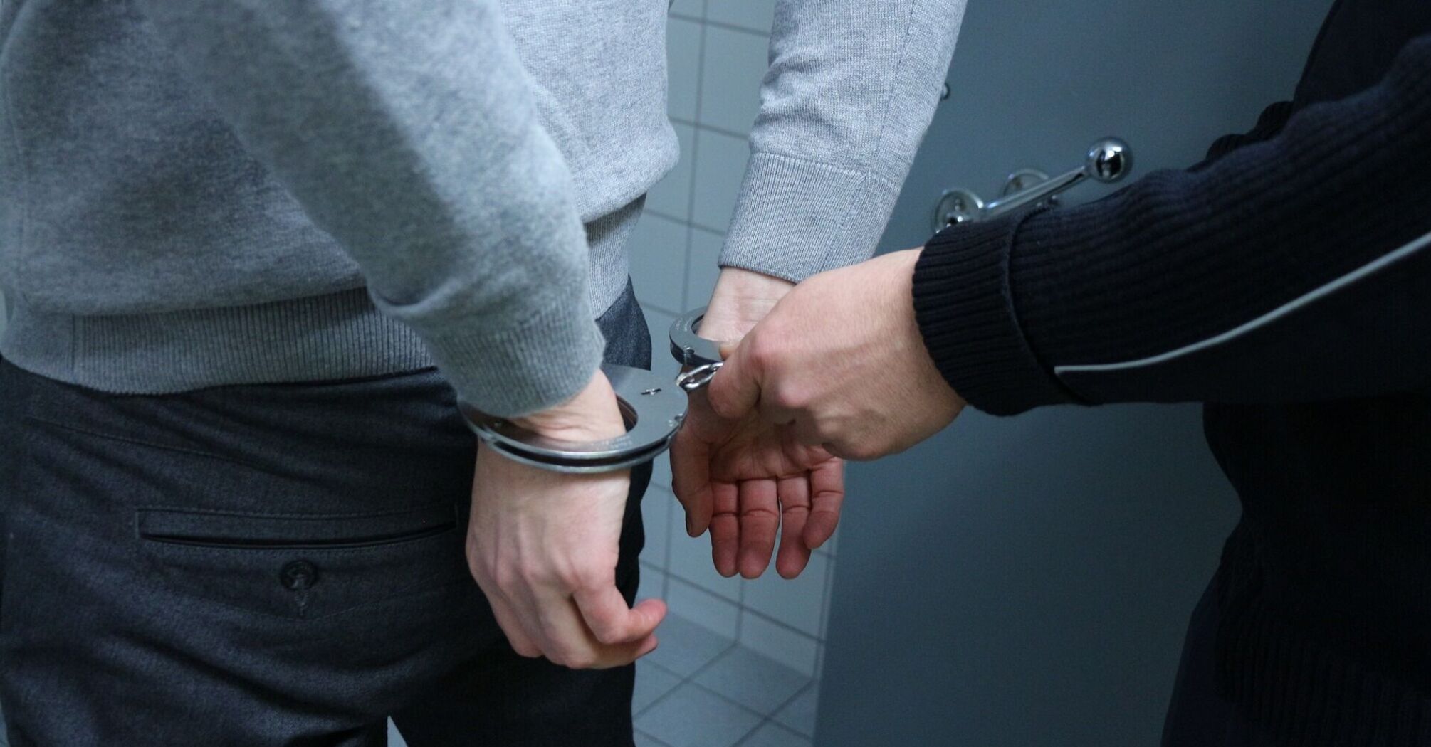 Man in handcuffs being detained by a police officer