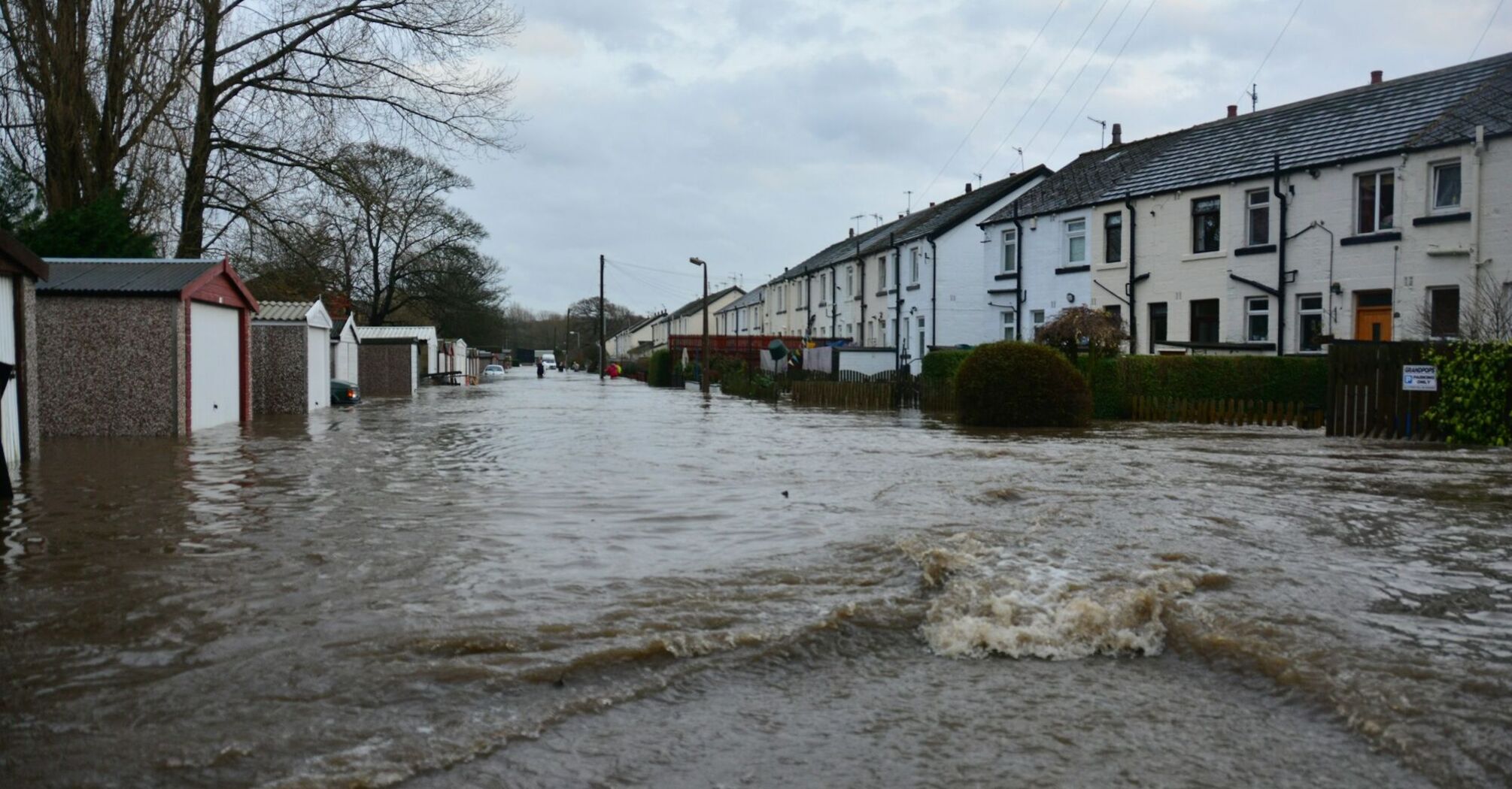 Flooded residential street in northern England with houses and garages submerged in water