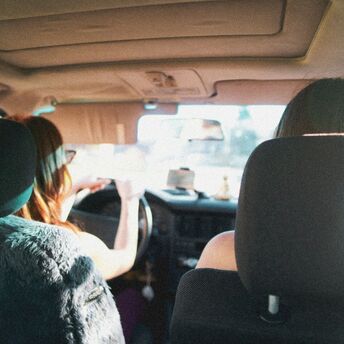Two women driving inside a car on a sunny day