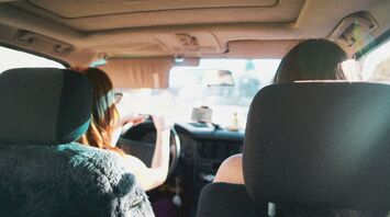 Two women driving inside a car on a sunny day