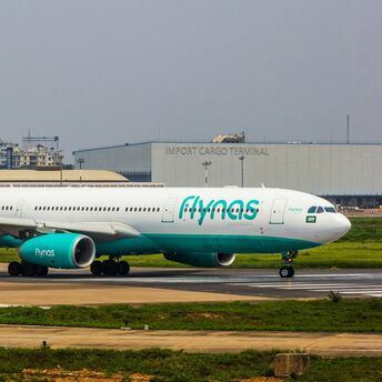 A flynas airplane on the runway at an international airport, highlighting the airline's operations