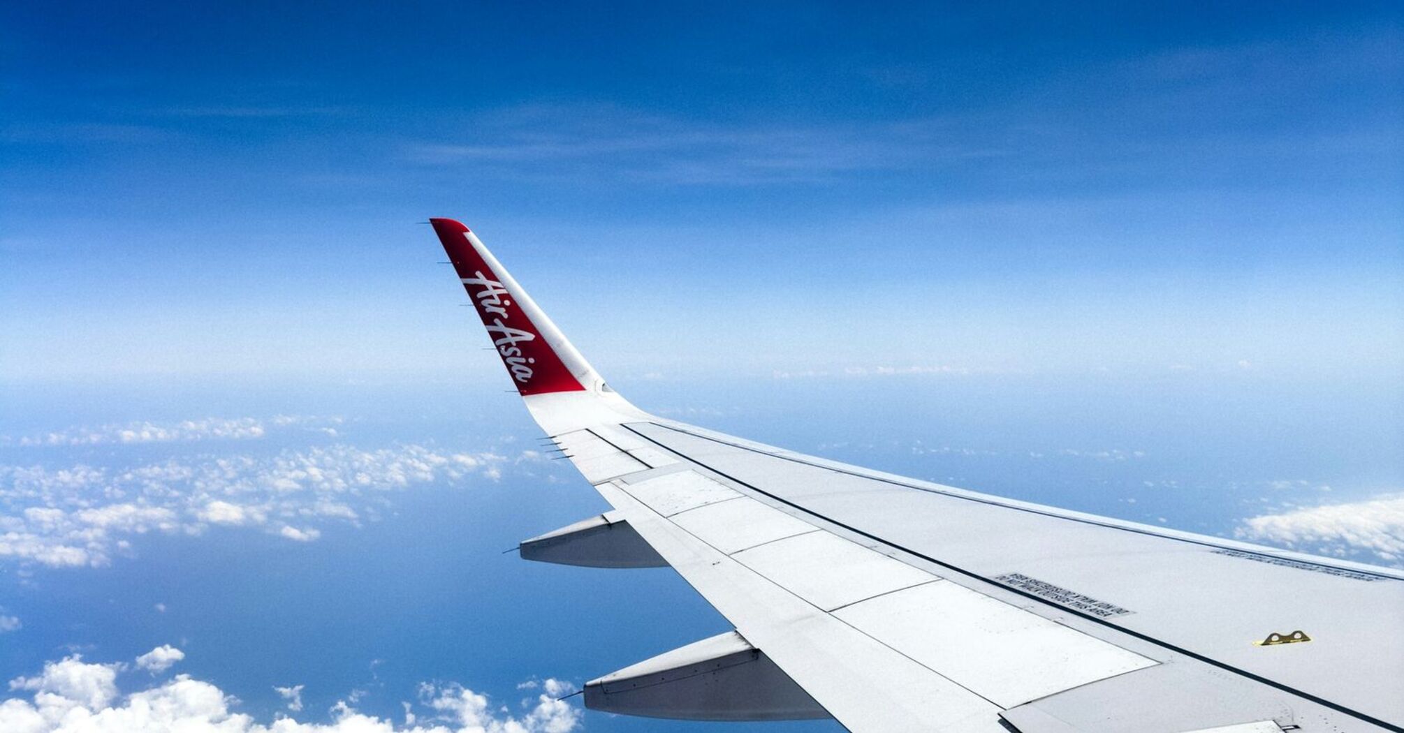 AirAsia airplane wing flying over tropical islands and clear blue waters