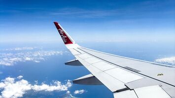 AirAsia airplane wing flying over tropical islands and clear blue waters