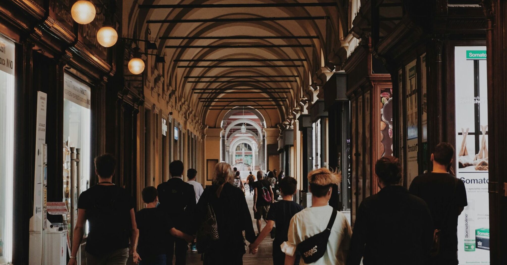 People walking under historic arched passageways in the city of Turin, Italy