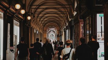 People walking under historic arched passageways in the city of Turin, Italy