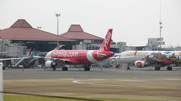 AirAsia aircraft parked at the terminal with boarding equipment at an airport