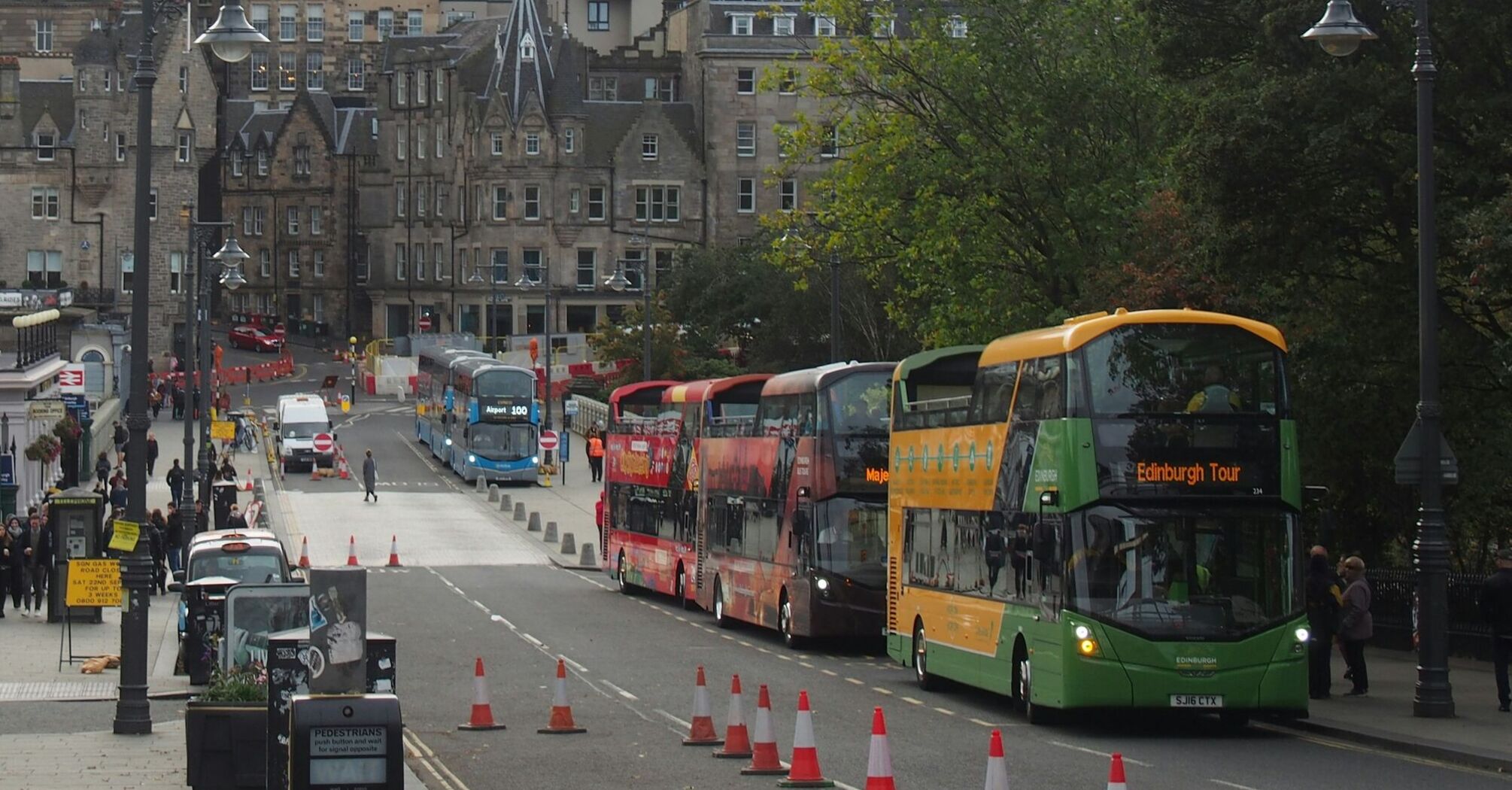 A busy street in Edinburgh featuring buses, historic buildings, and pedestrians