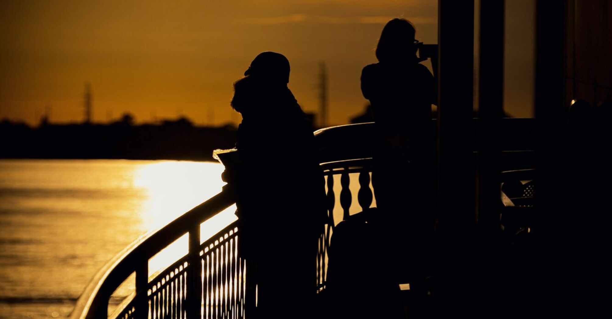 Silhouetted travelers enjoying a river cruise during a golden sunset