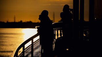 Silhouetted travelers enjoying a river cruise during a golden sunset