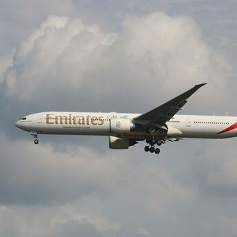Emirates aircraft in flight under cloudy skies