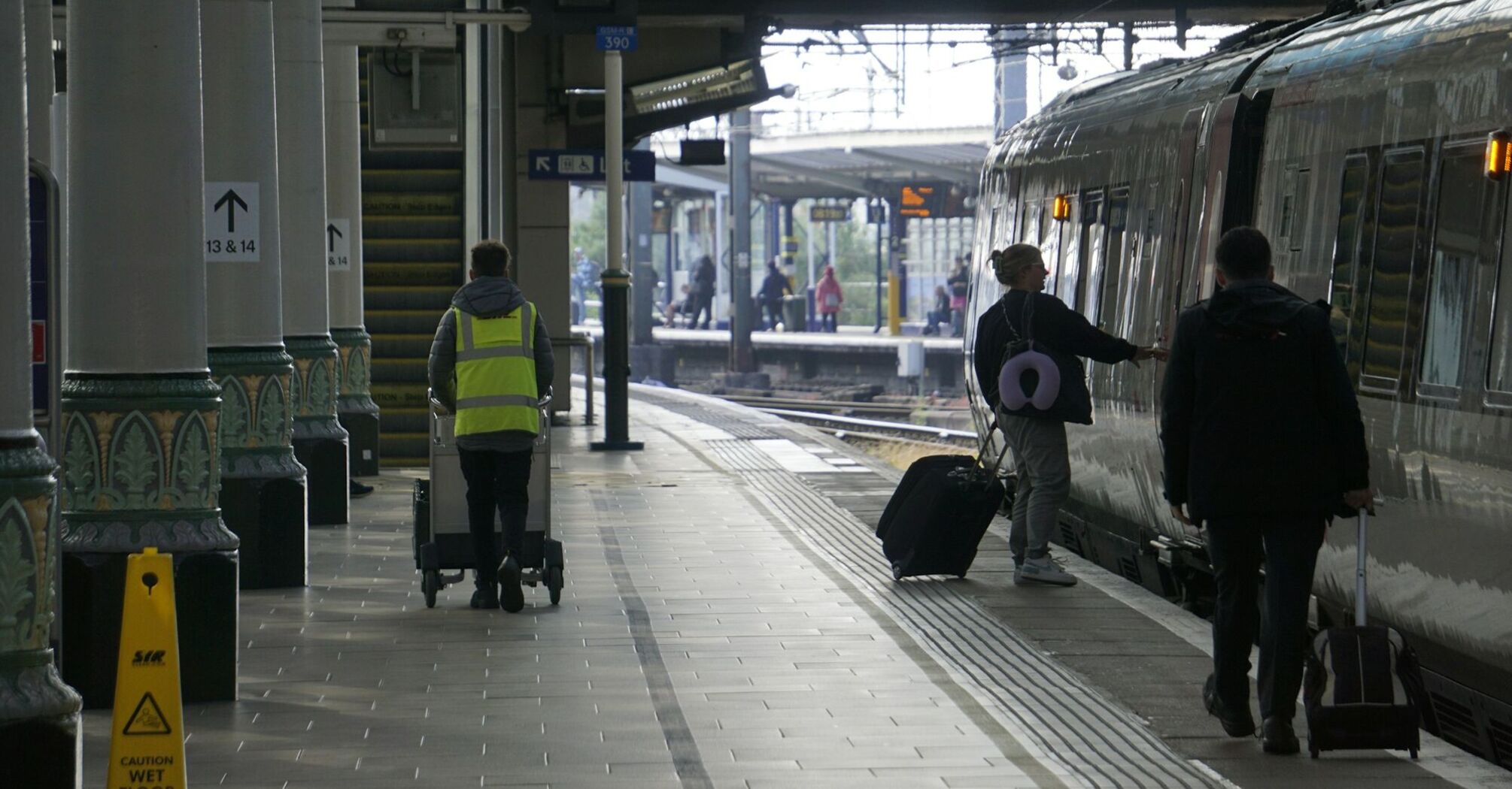 Passengers boarding a train at a busy UK railway station platform