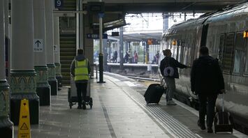 Passengers boarding a train at a busy UK railway station platform