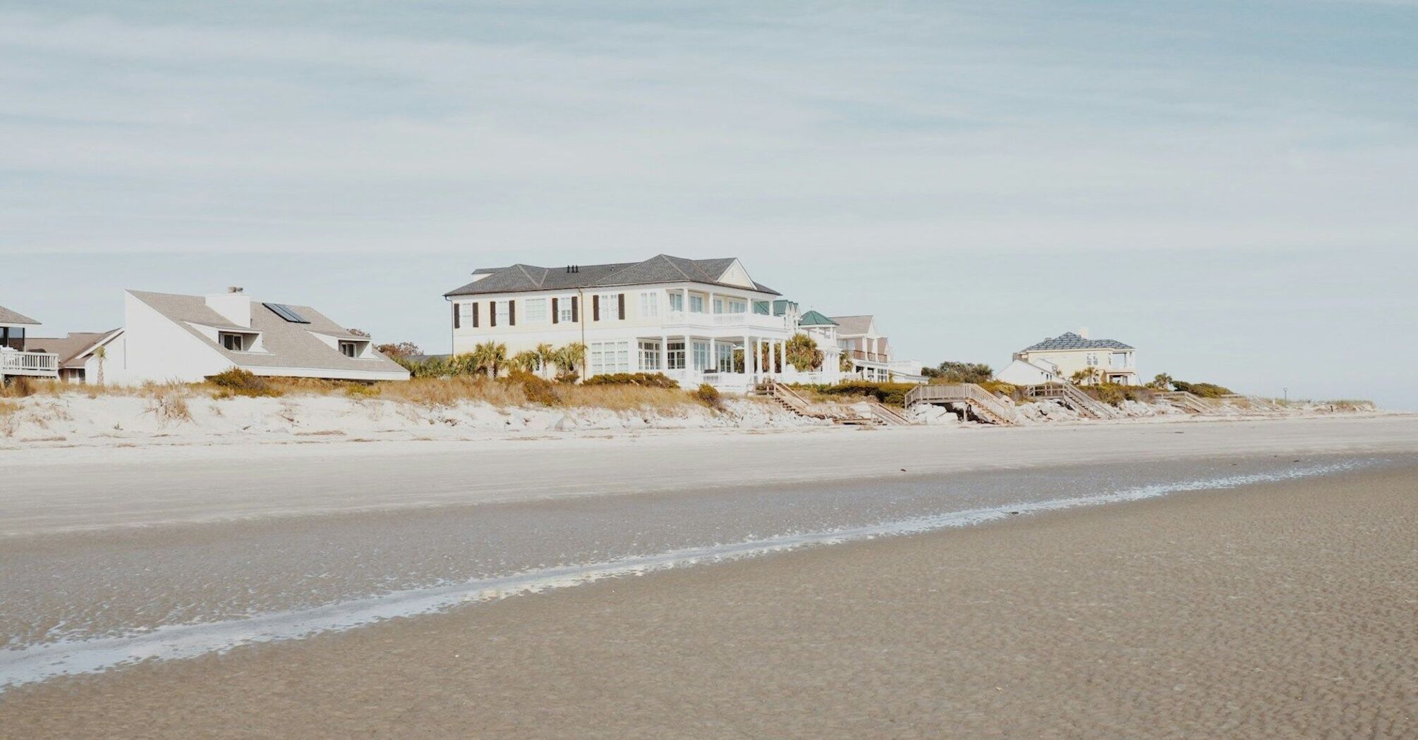 Beachfront vacation homes with ocean views on a sandy coastline under a clear blue sky