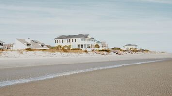 Beachfront vacation homes with ocean views on a sandy coastline under a clear blue sky