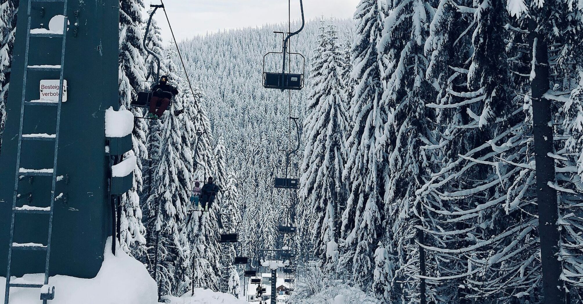 A ski lift surrounded by snow-covered trees in a serene mountain setting