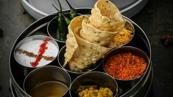 A traditional Indian meal served with papad, chutneys, and a pressure-cooked curry, showcasing vibrant and rich flavors