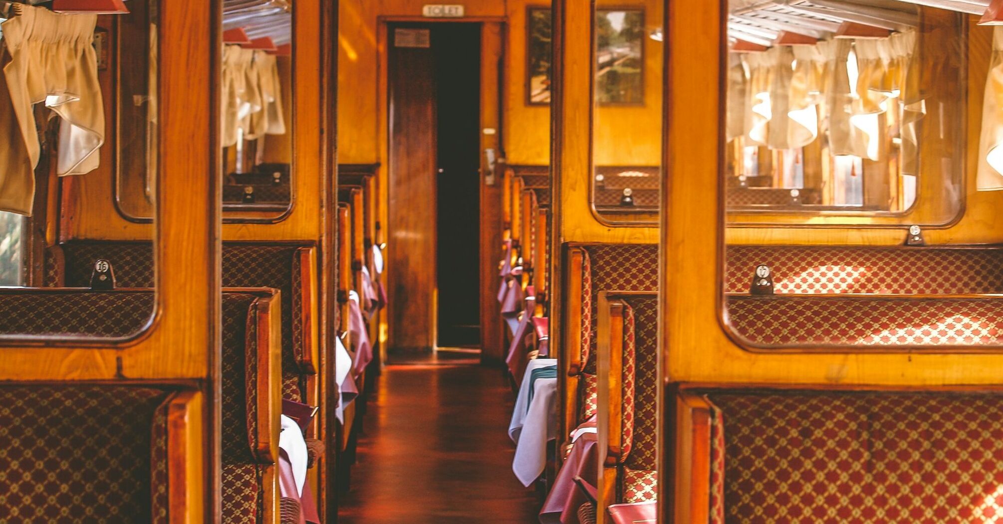 Vintage railway carriage interior with classic wooden design and patterned seating, evoking the charm of historic train travel