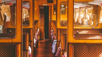 Vintage railway carriage interior with classic wooden design and patterned seating, evoking the charm of historic train travel
