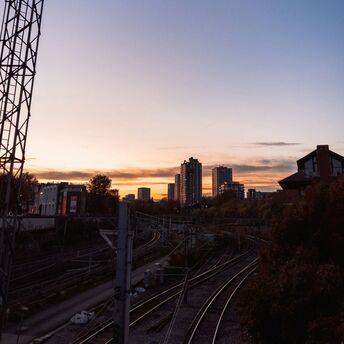 A railway track at sunset with a city skyline in the background, illustrating urban transport infrastructure
