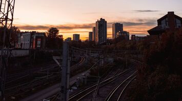 A railway track at sunset with a city skyline in the background, illustrating urban transport infrastructure