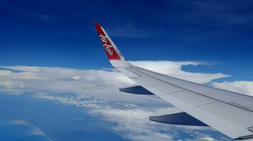 AirAsia wing view from a plane flying above a coastline under a blue sky