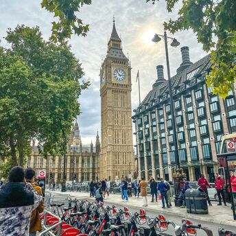 A street view of Big Ben and Westminster in London, with Santander bicycles and people in the foreground