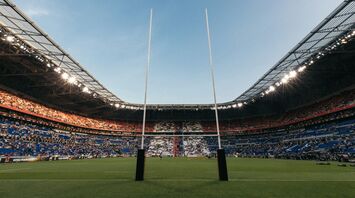 Rugby stadium with goalposts and a partially filled crowd during daylight