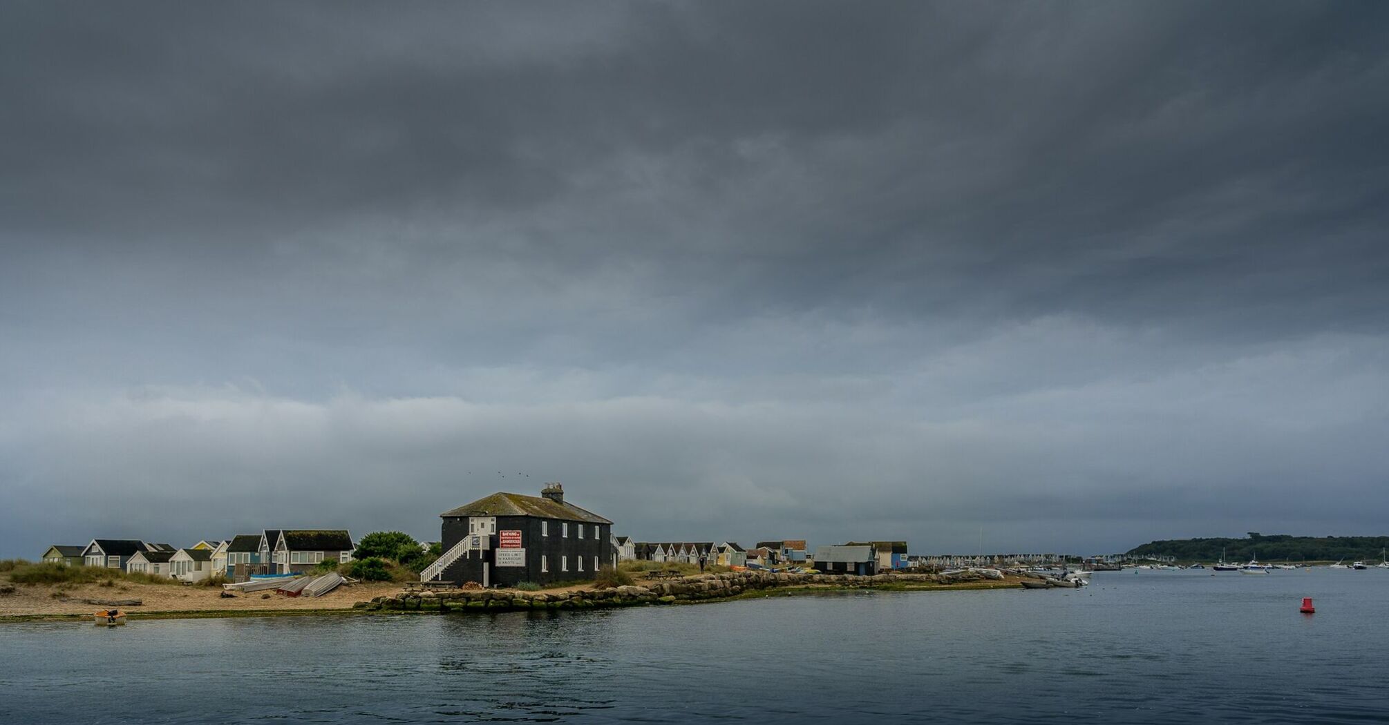 Coastal village under dark storm clouds with waves lapping at the shore