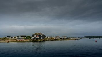 Coastal village under dark storm clouds with waves lapping at the shore