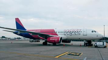A Wizz Air airplane parked at the airport with visible branding and ground support equipment nearby