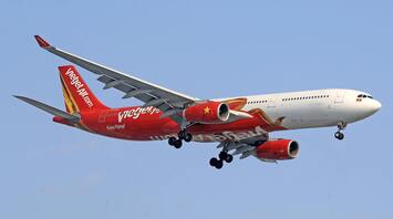 A Vietjet aircraft in flight against a clear blue sky, showcasing the airline's red and white livery