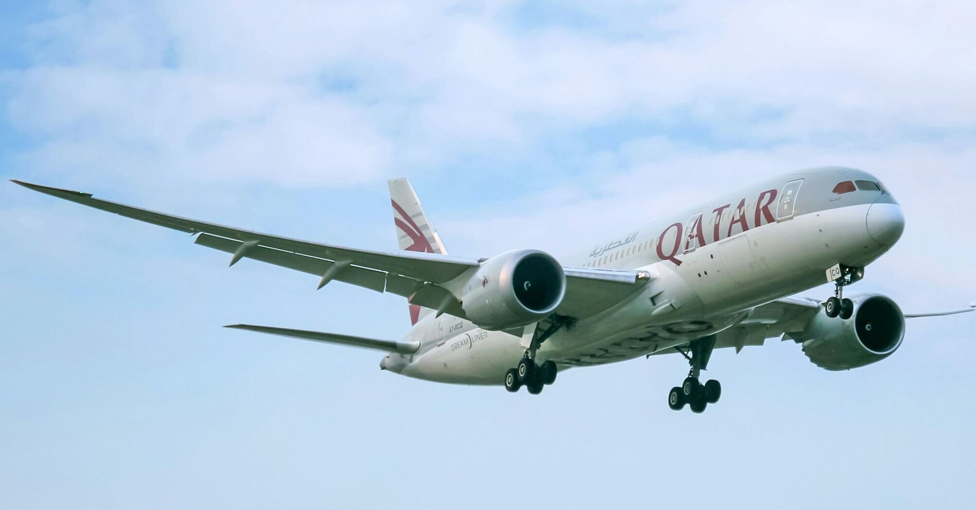 Qatar Airways airplane mid-flight against a clear sky