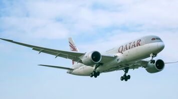 Qatar Airways airplane mid-flight against a clear sky